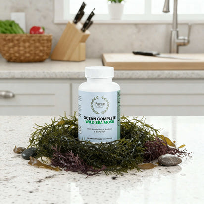 Bottle of Paean Ocean Complete Wild Sea Moss capsules surrounded by seaweed on kitchen counter
